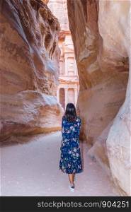 Young woman in colorful dress and hat walk around the Petra ruins with famous Al-Khazneh (The Treasury).