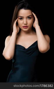 young woman in dark blue dress dress. on a black isolated background.she touches her face with her hand, touches her hair.. young woman in dark blue dress dress. on a black isolated background.she touches her face with her hand, touches her hair
