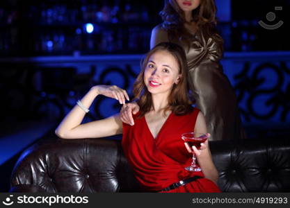 Young woman in evening dress in night club with a drink