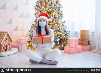 Young woman in facemask with gifts on Christmas. Young woman in mask holding christmas present