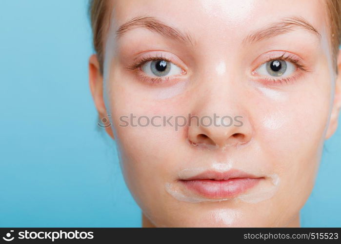 Young woman in facial peel off mask. Peeling. Beauty and skin care. Studio shot on blue background. Woman in facial peel off mask.