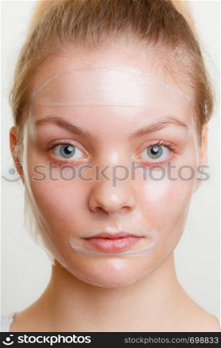 Young woman in facial peel off mask. Peeling. Beauty and skin care. Studio shot on gray. Woman in facial peel off mask.
