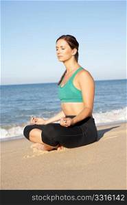 Young Woman In Fitness Clothing Meditating On Beach