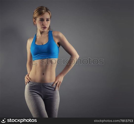 young woman in fitness dress. young beautiful woman in fitness dress standing in front of grey background