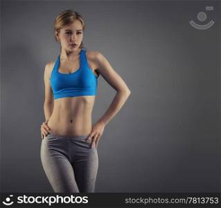 young woman in fitness dress. young beautiful woman in fitness dress standing in front of grey background