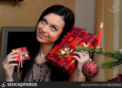 young woman in front of a christmas tree with christmas gifts