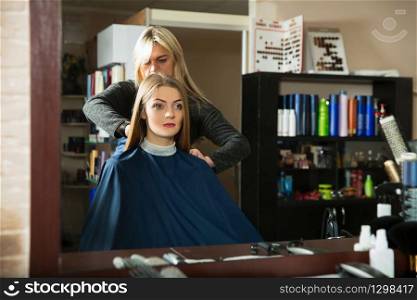 Young woman in front of the mirror prepares for hairdressing