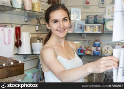 Young Woman In Gift Shop Choosing Greetings Card