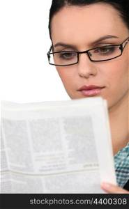 Young woman in glasses reading a newspaper