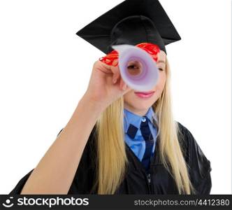 Young woman in graduation gown looking through diploma