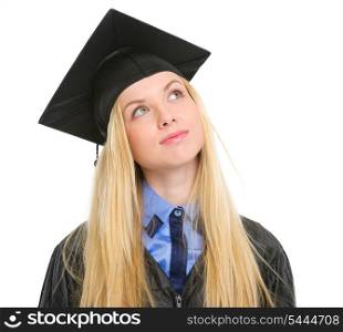Young woman in graduation gown looking up on copy space