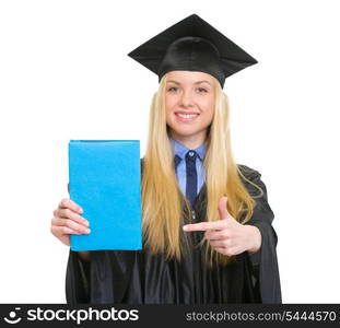 Young woman in graduation gown pointing book