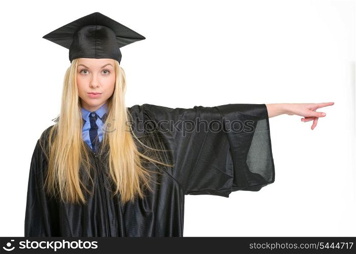 Young woman in graduation gown pointing on copy space