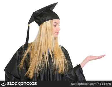 Young woman in graduation gown presenting something on empty palm