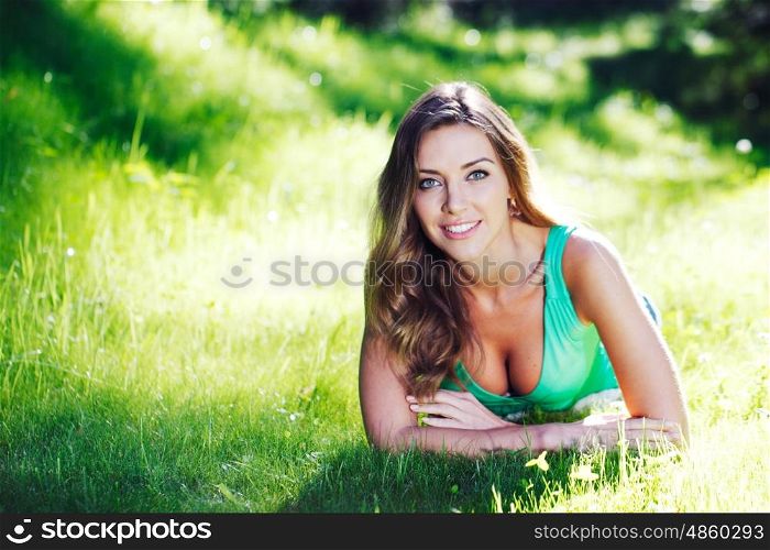 young woman in green dress lying on grass. beautiful young woman in green dress lying on grass