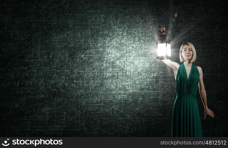 Young woman in green dress with lantern in darkness. Bright ideas