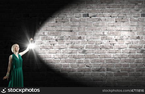 Young woman in green dress with lantern in darkness. Lost in darkness