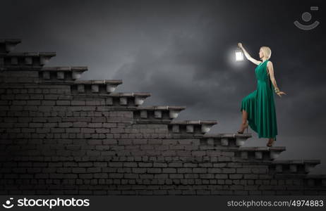 Young woman in green dress with lantern in darkness. Lost in darkness