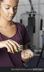 Young Woman In Gym Taking Tablets