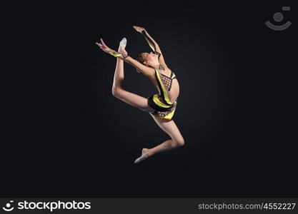 Young woman in gymnast suit posing. Young cute woman in gymnast suit show athletic skill on black background