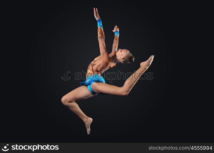 Young woman in gymnast suit posing. Young cute woman in gymnast suit show athletic skill on black background