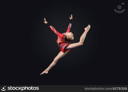Young woman in gymnast suit posing. Young cute woman in gymnast suit show athletic skill on black background