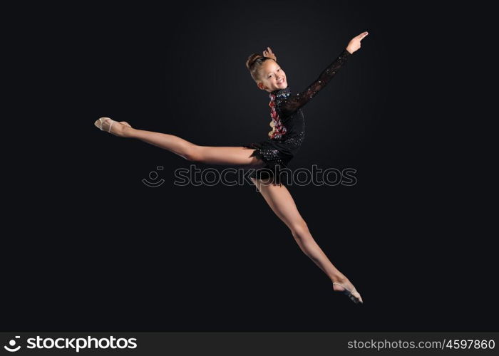 Young woman in gymnast suit posing. Young cute woman in gymnast suit show athletic skill on black background