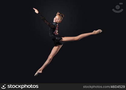 Young woman in gymnast suit posing. Young cute woman in gymnast suit show athletic skill on black background