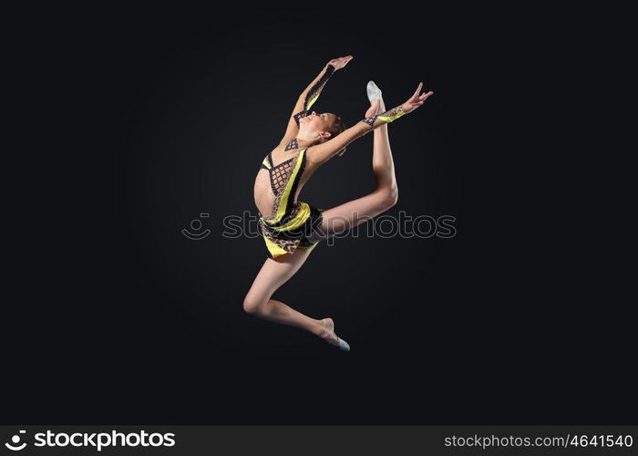 Young woman in gymnast suit posing. Young cute woman in gymnast suit show athletic skill on black background