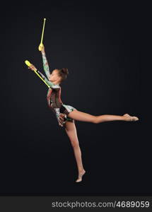 Young woman in gymnast suit posing. Young cute woman in gymnast suit show athletic skill on black background