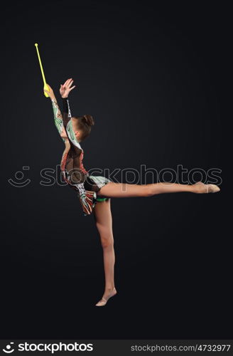 Young woman in gymnast suit posing. Young cute woman in gymnast suit show athletic skill on black background