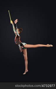 Young woman in gymnast suit posing. Young cute woman in gymnast suit show athletic skill on black background