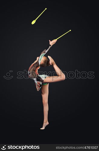 Young woman in gymnast suit posing. Young cute woman in gymnast suit show athletic skill on black background