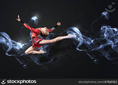 Young woman in gymnast suit posing. Young cute woman in gymnast suit show athletic skill on black background