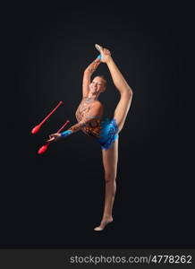 Young woman in gymnast suit posing. Young cute woman in gymnast suit show athletic skill on black background