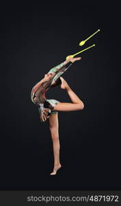 Young woman in gymnast suit posing. Young cute woman in gymnast suit show athletic skill on black background