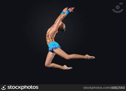 Young woman in gymnast suit posing. Young cute woman in gymnast suit show athletic skill on black background