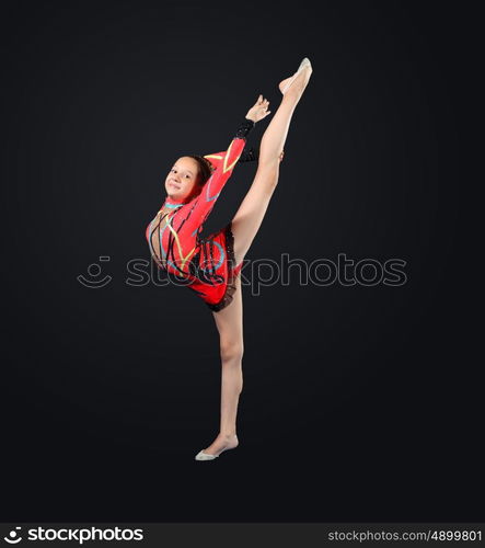 Young woman in gymnast suit posing. Young cute woman in gymnast suit show athletic skill on black background