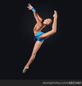 Young woman in gymnast suit posing. Young cute woman in gymnast suit show athletic skill on black background