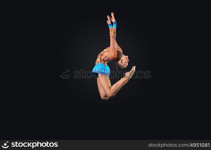 Young woman in gymnast suit posing. Young cute woman in gymnast suit show athletic skill on black background