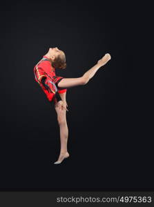 Young woman in gymnast suit posing. Young cute woman in gymnast suit show athletic skill on black background