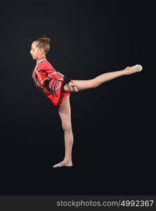 Young woman in gymnast suit posing. Young cute woman in gymnast suit show athletic skill on black background