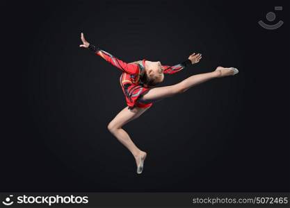 Young woman in gymnast suit posing. Young cute woman in gymnast suit show athletic skill on black background