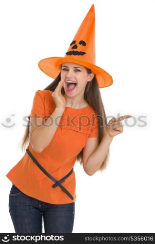 Young woman in Halloween hat whispering and pointing on copy space