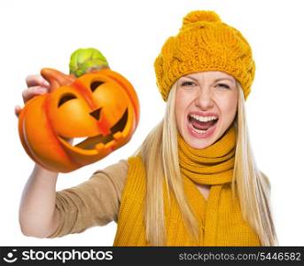 Young woman in hat and scarf scaring with jack-o-lantern