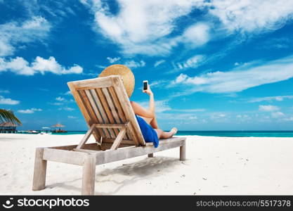 Young woman in hat with mobile phone at the beach