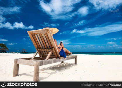 Young woman in hat with mobile phone at the beach