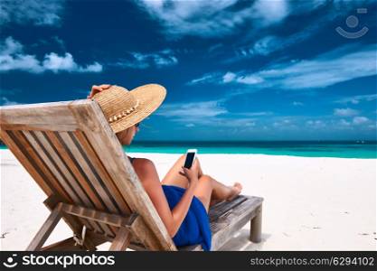 Young woman in hat with mobile phone at the beach