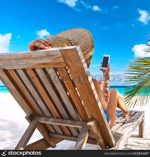 Young woman in hat with mobile phone at the beach