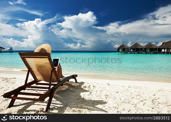 Young woman in hat with tablet pc at the beach